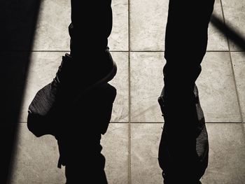 Low section of silhouette woman standing on tiled floor