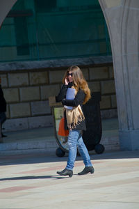 Full length of woman walking against building in city