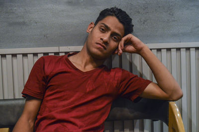 Portrait of young man standing against railing