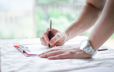 Close-up of woman hand holding paper on table