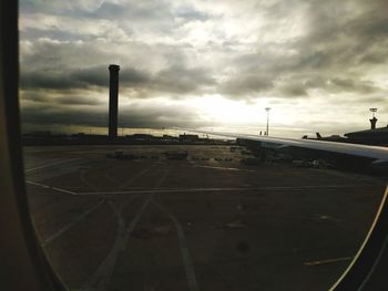 Airplane flying over airport runway against sky