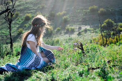 Girl with shawl sitting on field