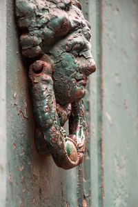 Close-up of old green knocker on door