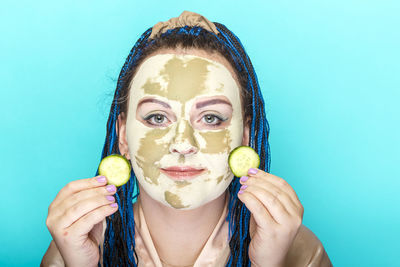 Portrait of woman holding apple against blue background