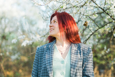 Young woman standing against trees