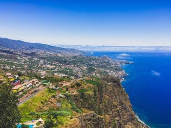 Scenic view of sea and mountains against clear blue sky