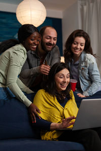 Friends using phone while sitting on sofa at home