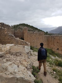 Rear view of man looking at mountain against sky