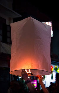 People holding illuminated lantern at night