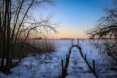 Scenic view of snow covered lake against sky during sunset