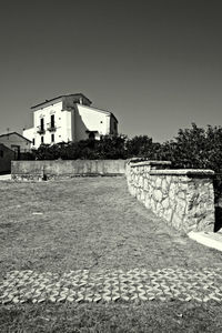 Footpath by buildings against clear sky