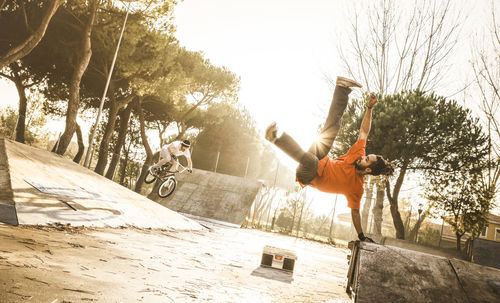 People jumping by trees against clear sky