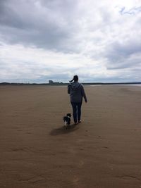 Rear view of man standing on beach against sky