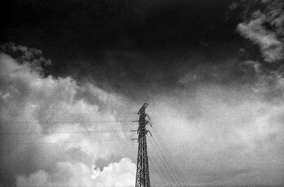 Low angle view of power lines against cloudy sky