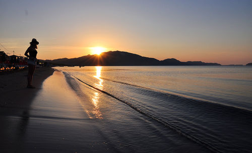 Silhouette person on beach against sky during sunset