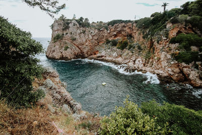 Scenic view of rocks by sea against sky