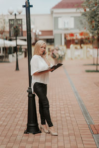 A confident businesswoman working outdoors over the project and talking on the phone with clients