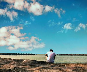 Rear view of man sitting at beach