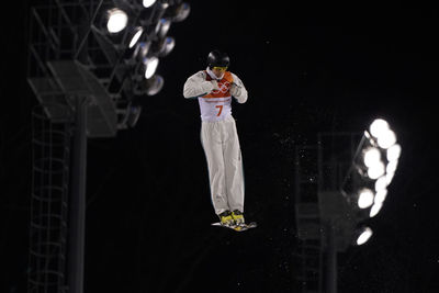 Full length of woman standing against illuminated lights against sky at night