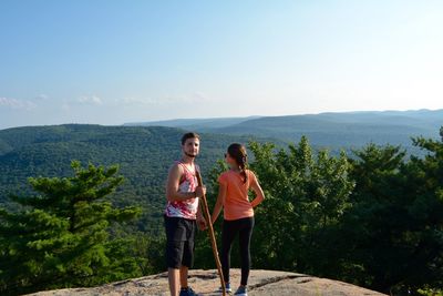 Full length of couple standing on cliff against sky