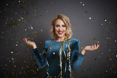 Portrait of smiling woman standing against gray background