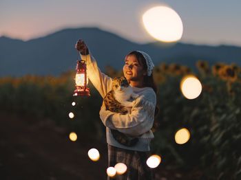 Rear view of woman holding illuminated string lights