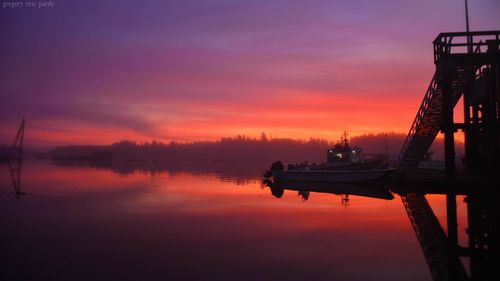 Silhouette boats moored at harbor against sky during sunset