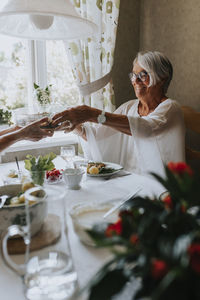 Smiling senior woman having meal at table