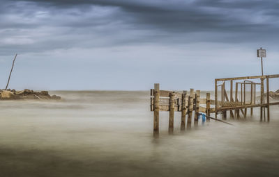 Wooden posts on beach against sky