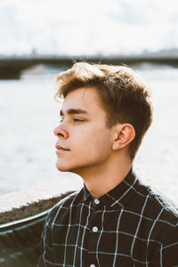 Young man looking away against sea and sky
