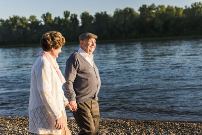 Happy senior couple walking hand in hand at riverside