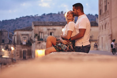 Young couple kissing against sky