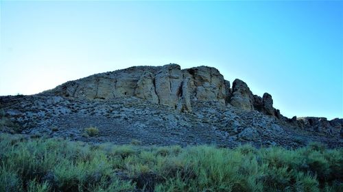 Low angle view of rocks against clear blue sky