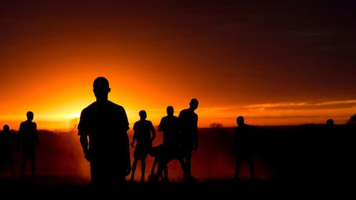 Silhouette people plying on land against clear sky during sunset