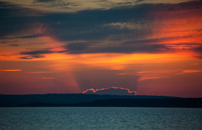 Scenic view of sea against dramatic sky during sunset