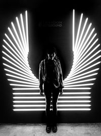 Full length of man standing against illuminated wall