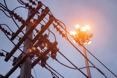 Low angle view of illuminated lights against sky at sunset