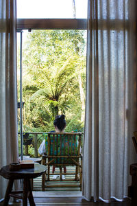 Rear view of woman seen through glass window