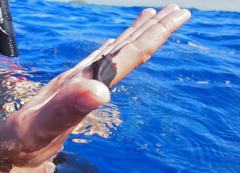 Midsection of person hand in sea