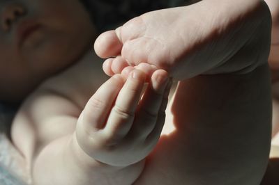 Low section of naked baby girl lying on bed at home
