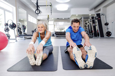 Senior man and mature woman exercising in fitness gym