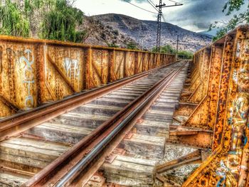 Railroad tracks by mountain against sky