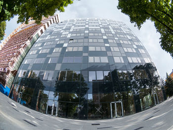 City street by modern buildings against sky