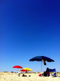 People on beach against clear blue sky