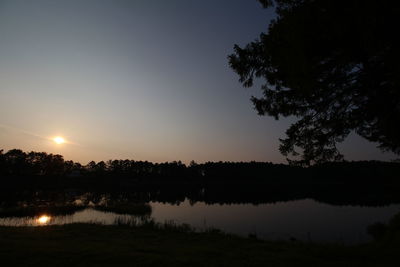 Reflection of trees in calm lake at sunset