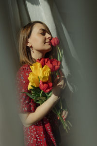 Young woman is playful natural beauty in red dress with  holding lush blooming tulips. spring mood