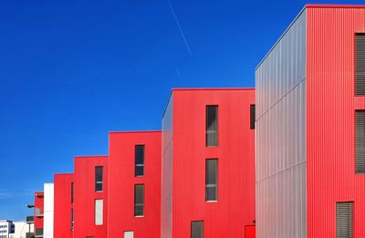 Low angle view of red building against clear blue sky