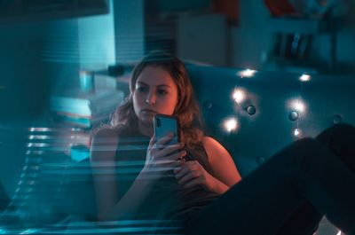 Young woman looking at illuminated window