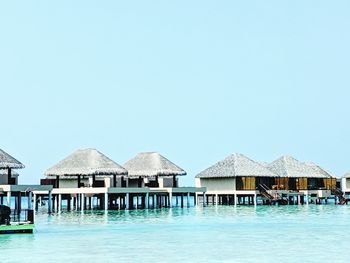 Stilt houses by swimming pool against clear sky