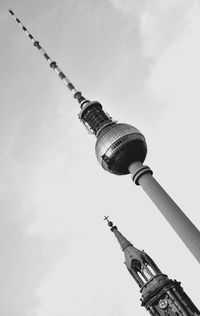 Low angle view of communications tower against cloudy sky